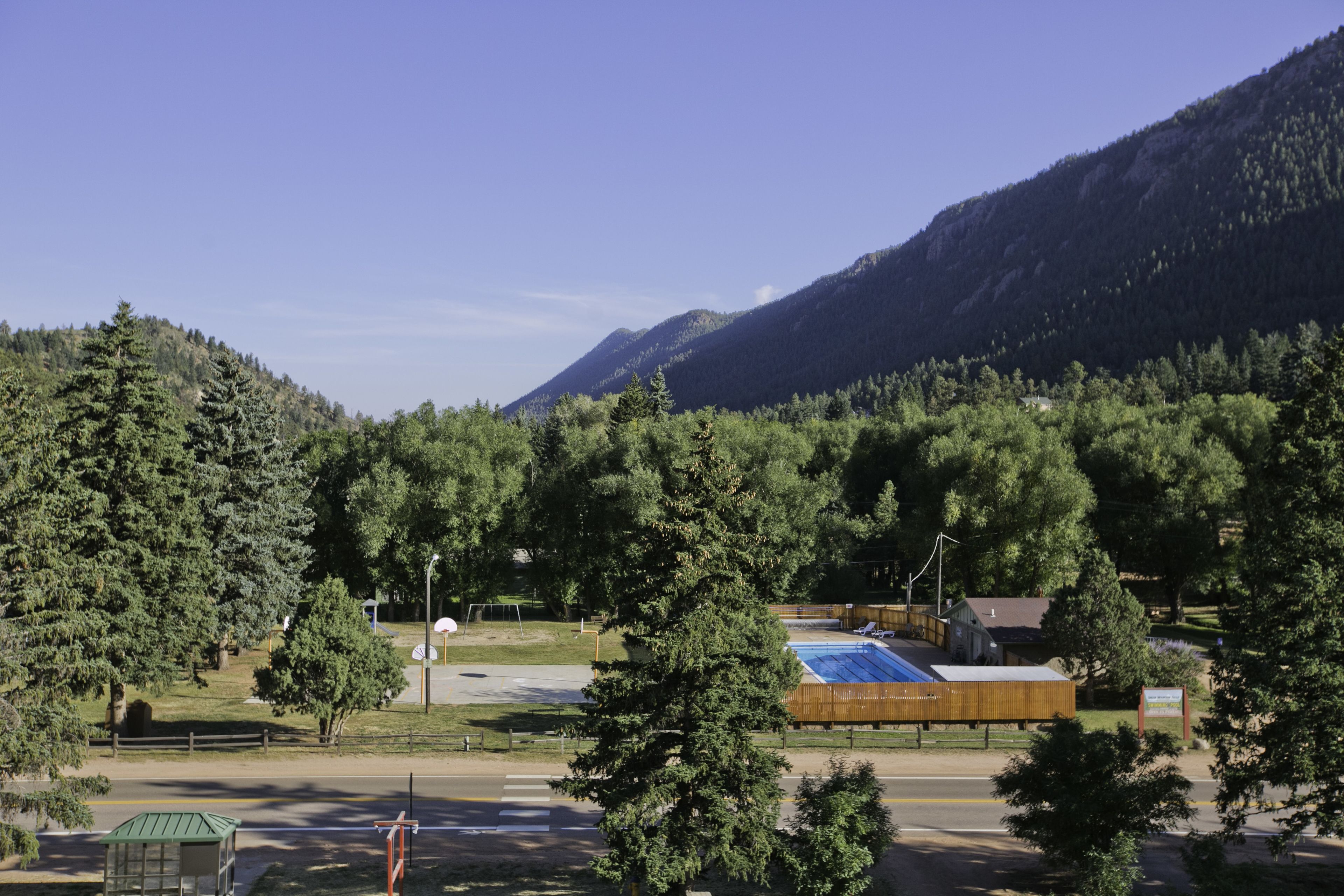 A mountain view with a swimming pool, a small building, and a fenced area.
