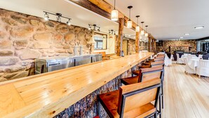 Eine Bar mit Steinwand, Holzbalken und verschiedenen Sitzgelegenheiten.