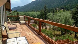 Eine Holzterrasse mit Sitzgelegenheiten und Blick auf eine gebirgige Landschaft.