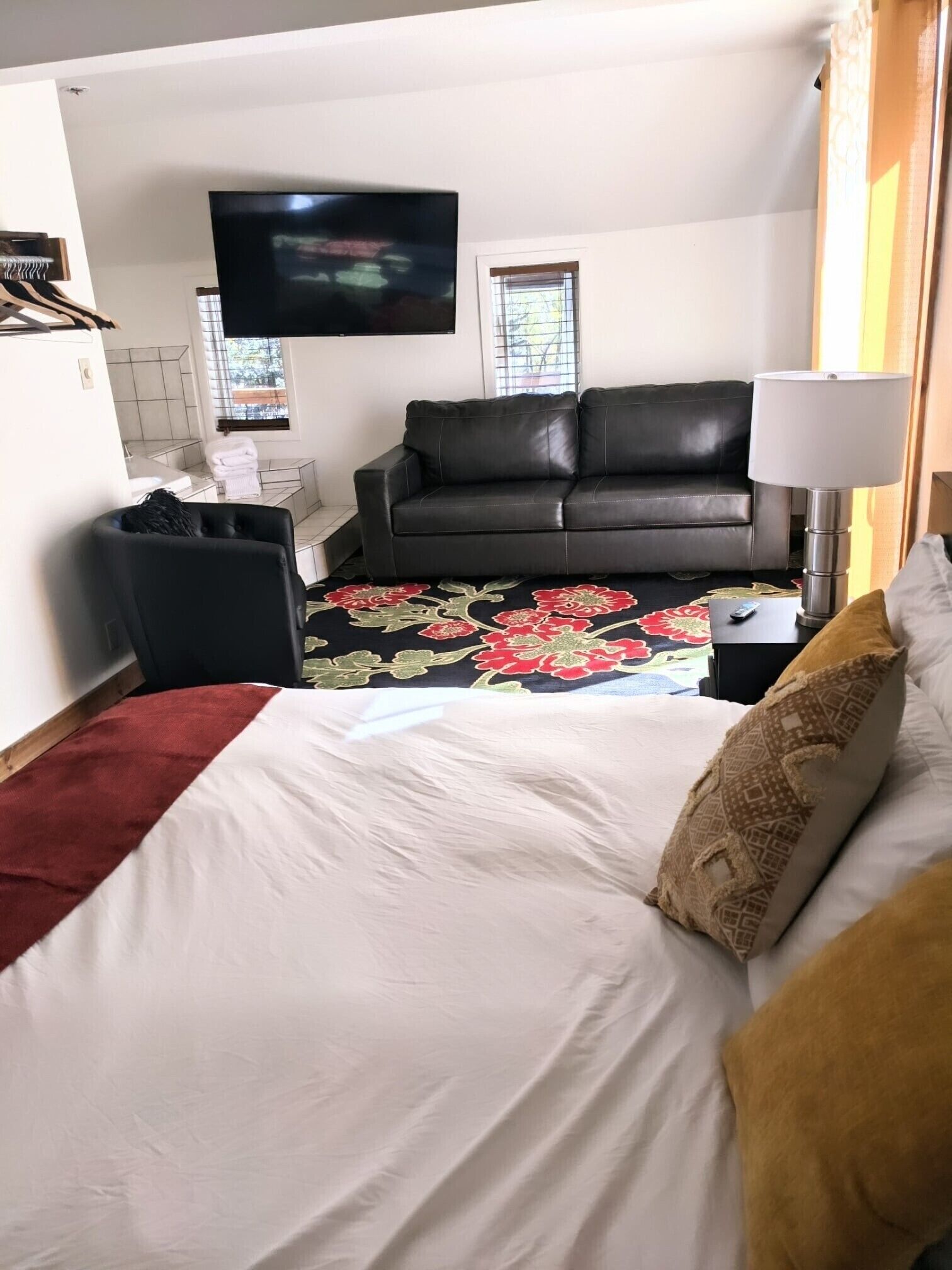 A hotel room with a bed, a sofa, a TV, and a window.