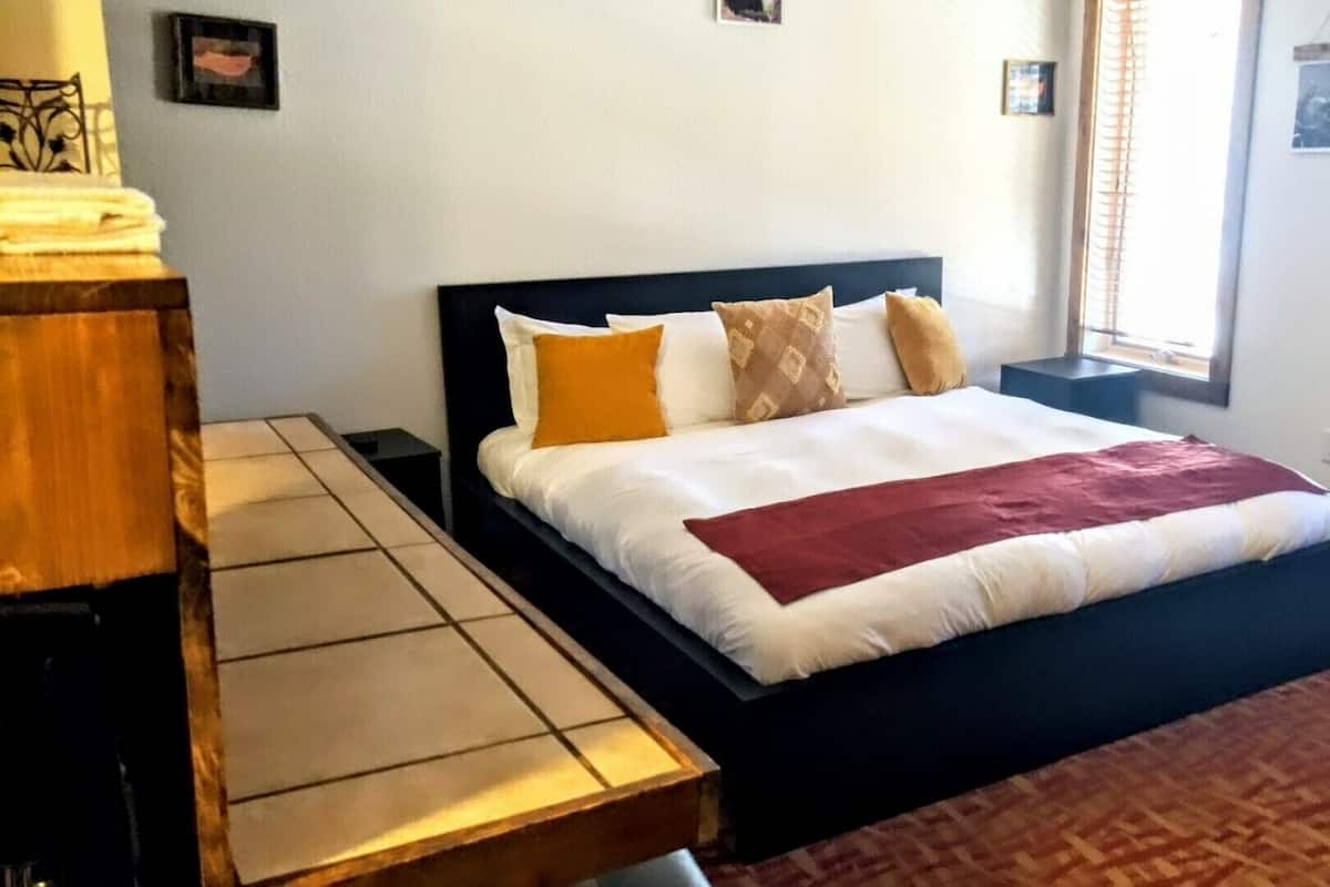 Una camera da letto con un letto, un comodino, una panca e una finestra con persiane.