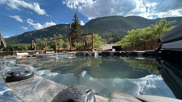 Ein Thermalbad mit Steinmöbeln und einer Holzpergola.