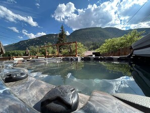 A hot spring area with stone seating and a wooden pergola. - The Green Mountain Falls Lodge (Green Mountain Falls)