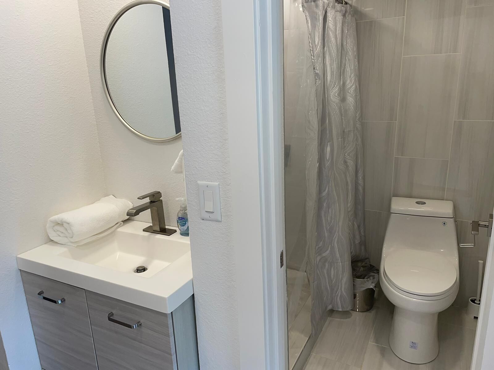 A bathroom with a white sink, a mirror, a toilet, and a shower curtain.