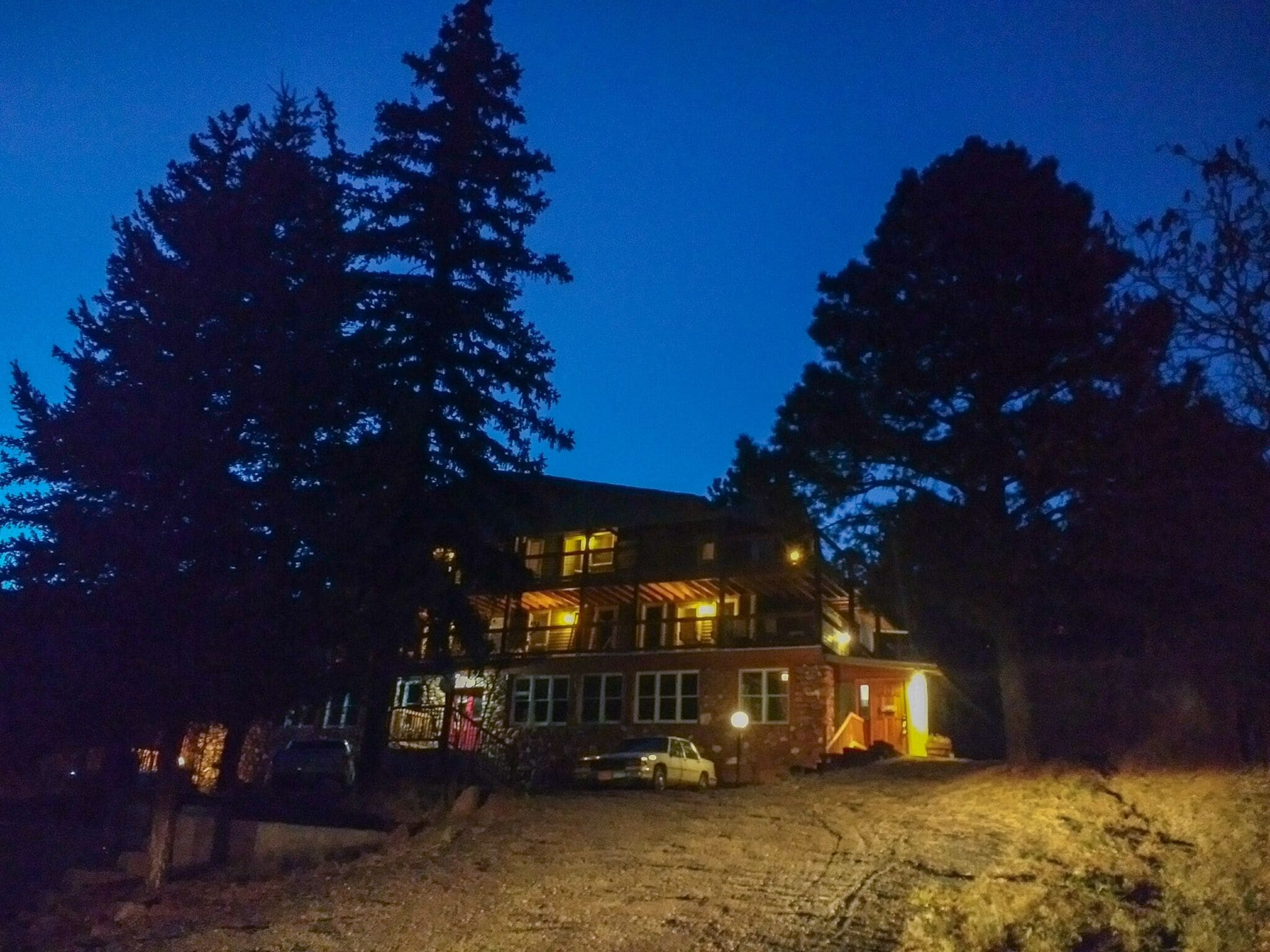 En tvåvåningsbyggnad med en stor balkong, omgiven av höga träd.