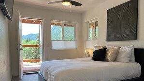 Ein Schlafzimmer mit Bett, Deckenventilator, Fenster und einer Tür zu einem Außenbereich.