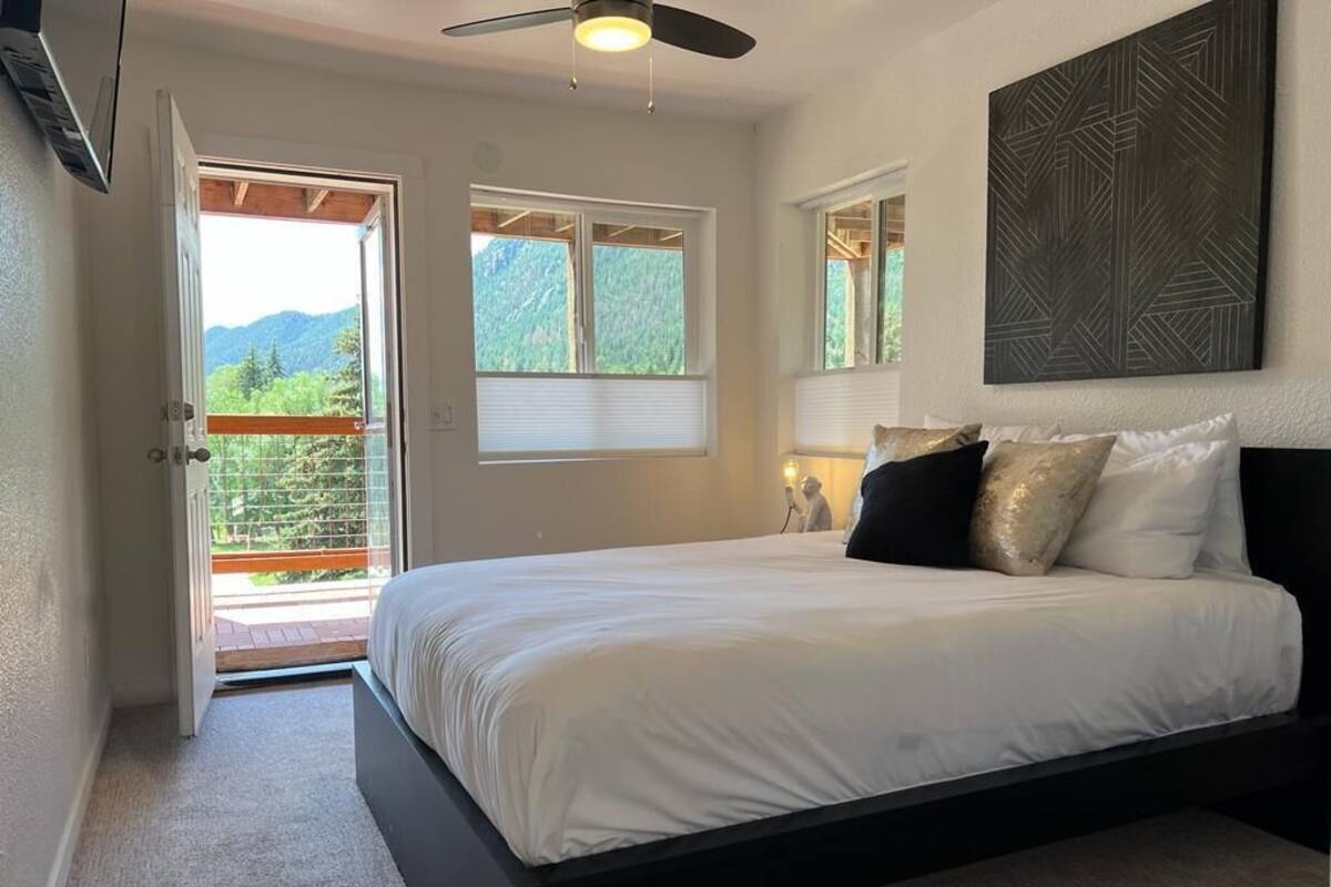 Una camera da letto con un letto, una ventola a soffitto, una finestra e una porta che dà su un'area esterna.