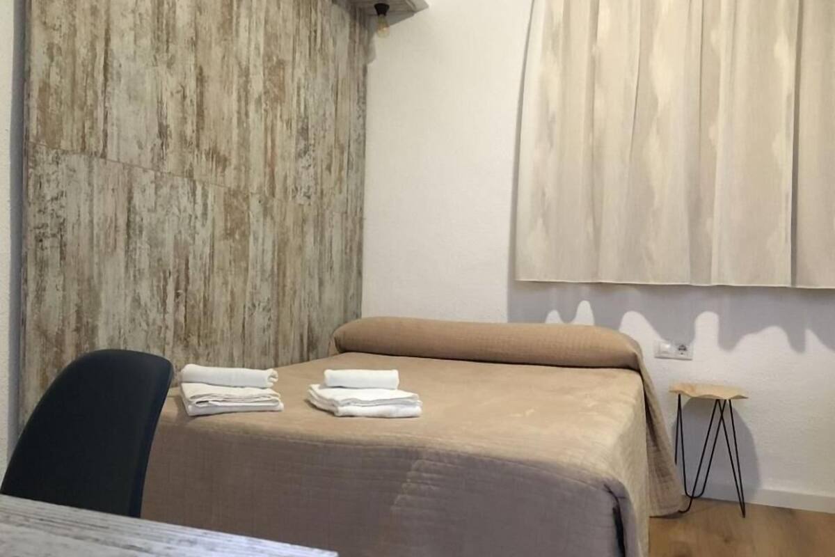 A room with a bed, a chair, and a small table.
