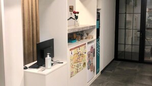 A reception area with a 'roomconcept' sign, a desk with a computer, a bottle of hand sanitizer, and a wall with a map. - Room Concept Hostel (Santo Domingo de la Calzada)
