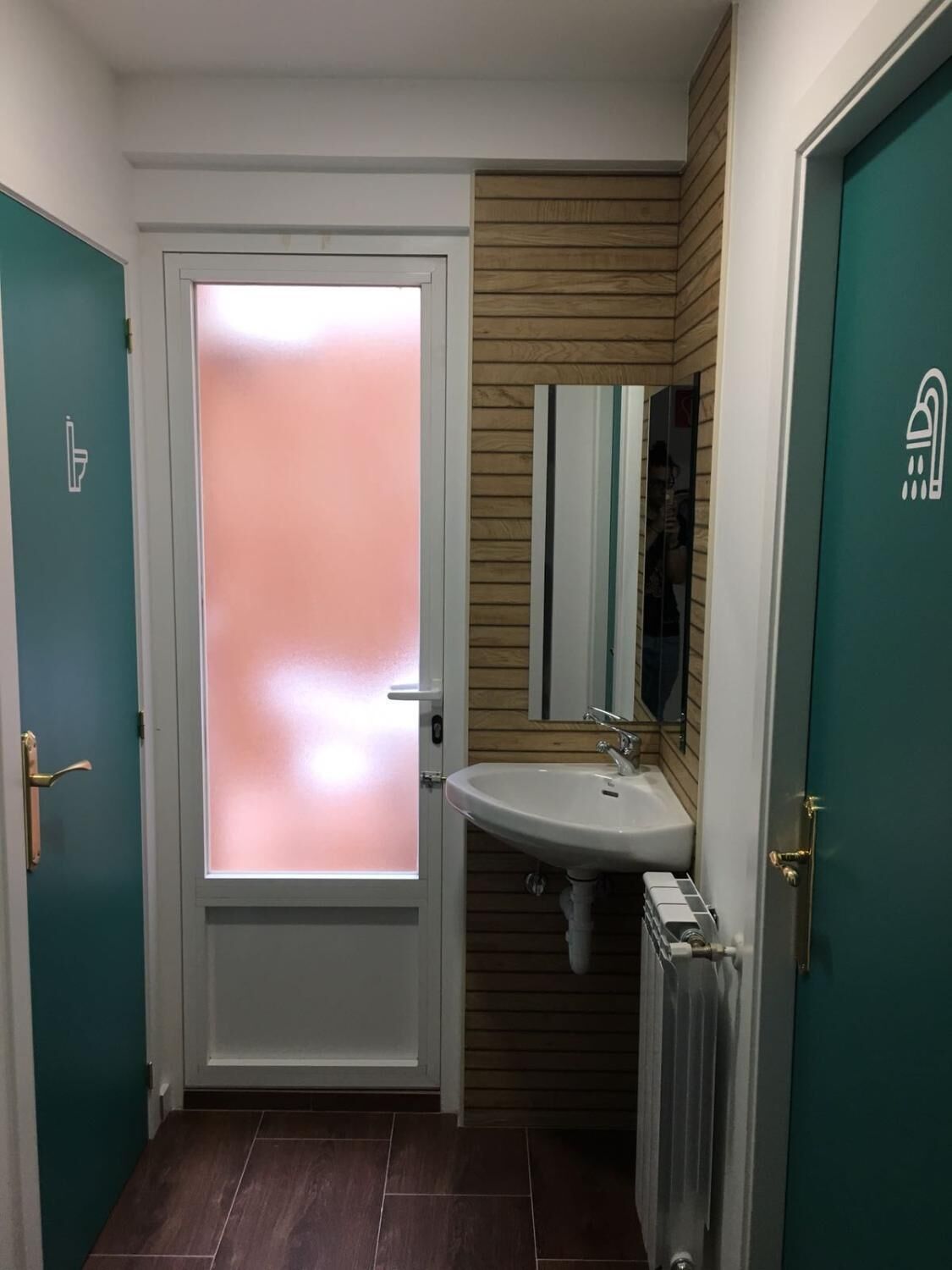 A bathroom with a white door, a sink, and a mirror.