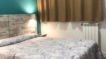 A bedroom with a bed, teal walls, a brown curtain, a white radiator, and a nightstand with a lamp.