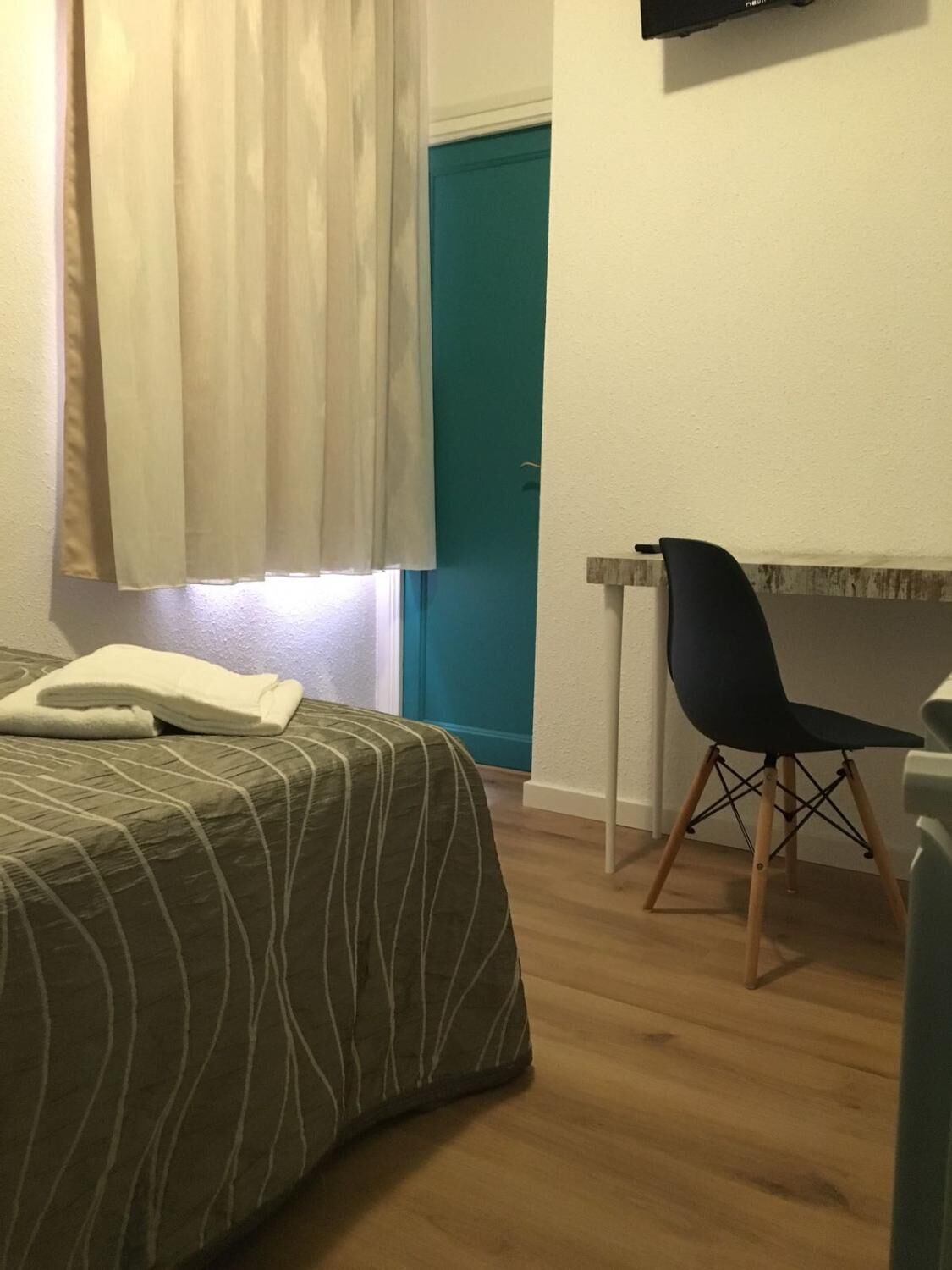 Un dormitorio con cama, escritorio y silla.