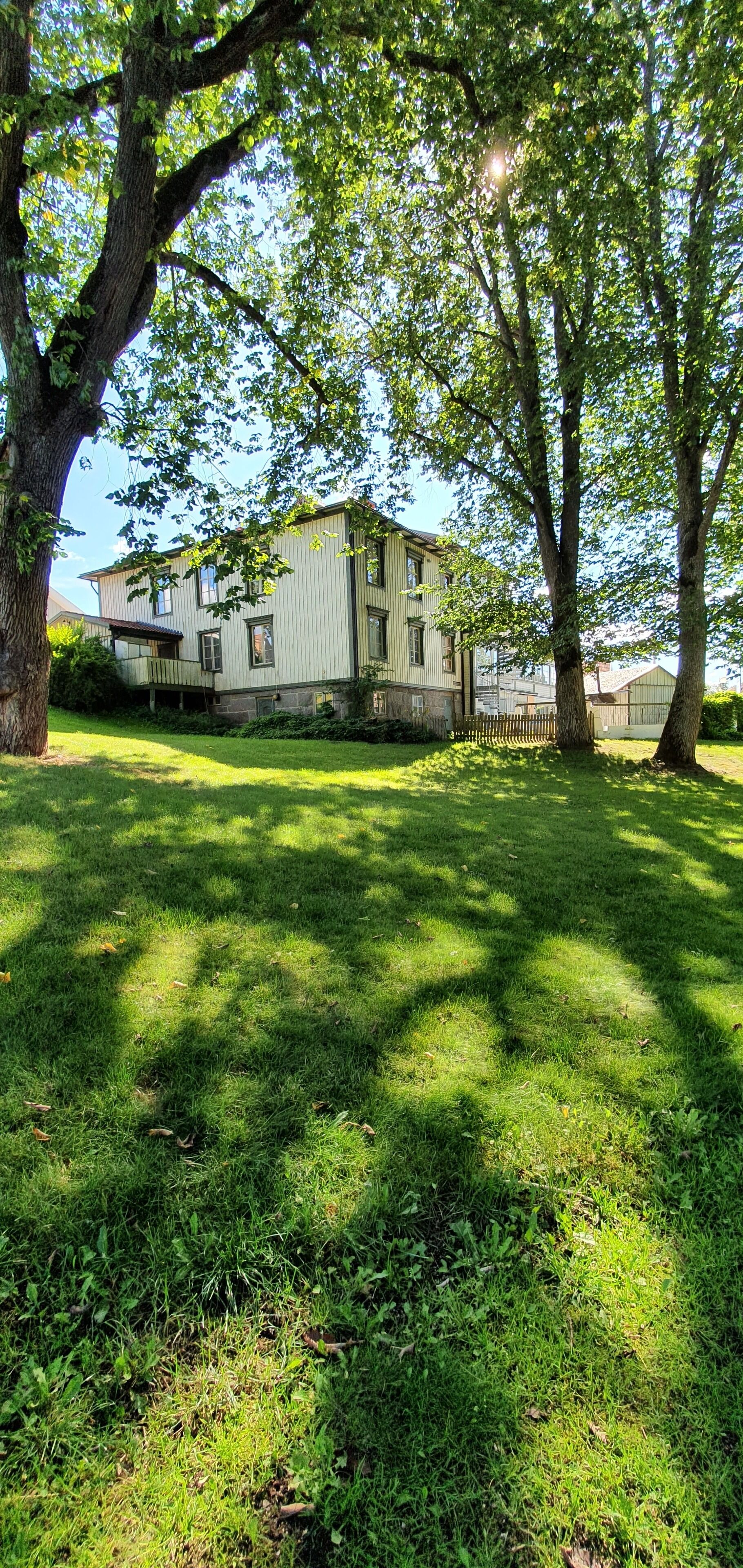 A two-story house with a large front yard, surrounded by trees.