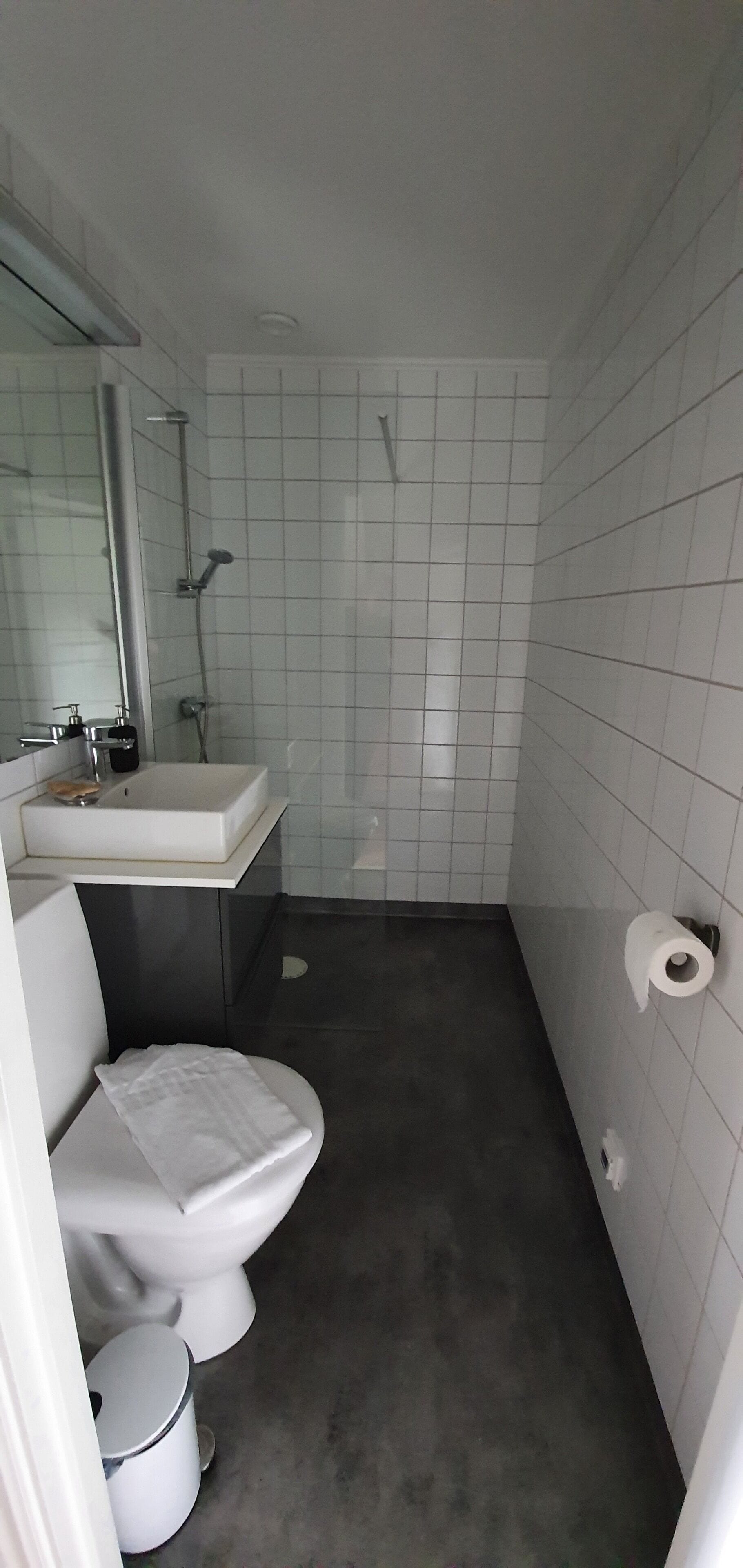 Un baño pequeño con lavamanos, inodoro y ducha blancos.
