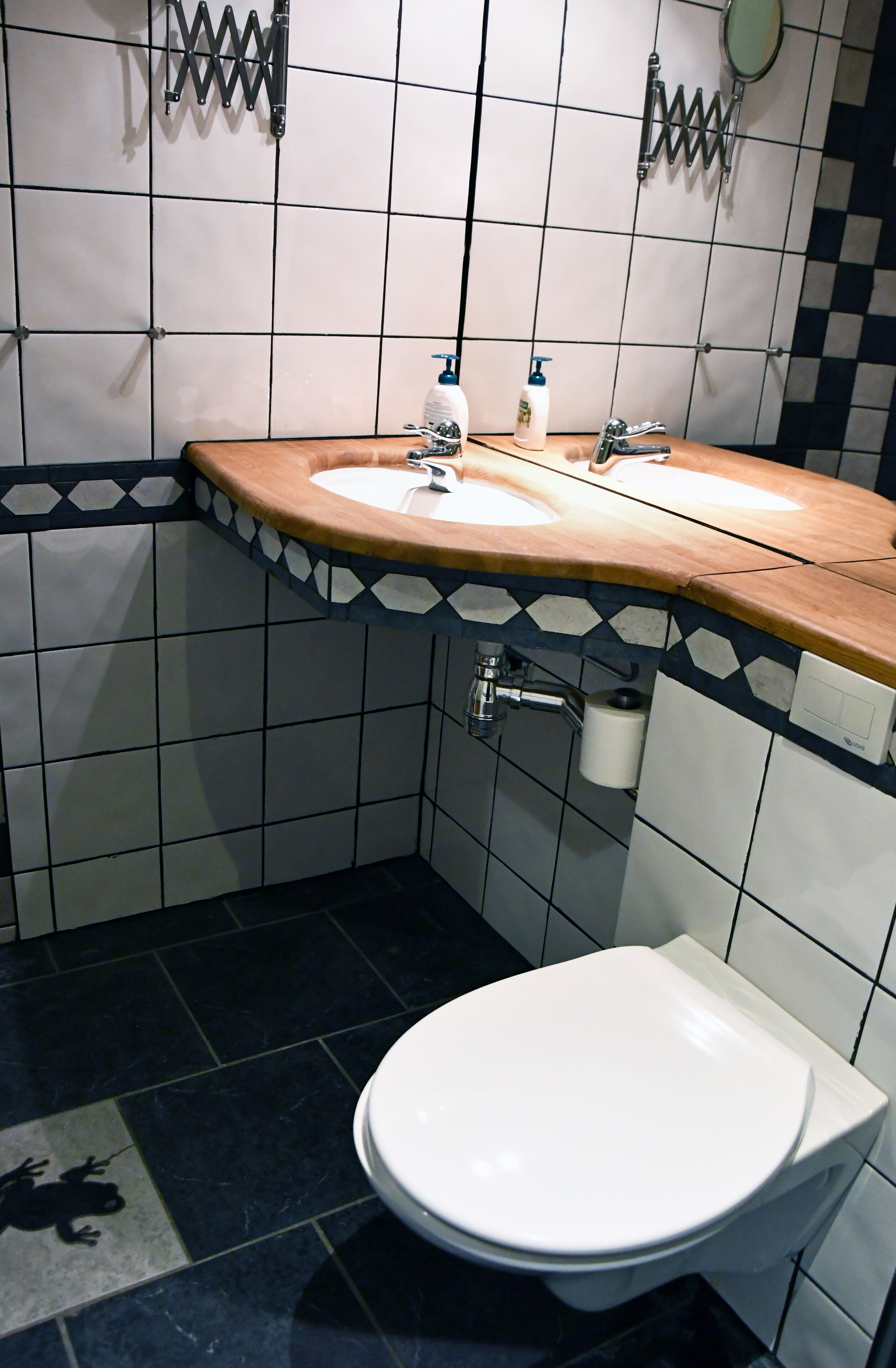 A bathroom with two sinks, a toilet, and a mirror.