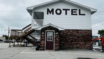 A motel with a prominent 'MOTEL' sign, a small brick extension, and a wooden staircase leading to a balcony.
