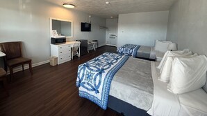 Une chambre d’hôtel avec deux lits, un bureau, une chaise, une télévision et une petite kitchenette.
