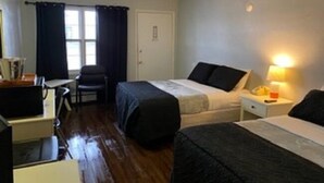 A small, simple room with two beds, a desk, and a chair.