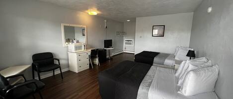 Een hotelkamer met een bed, een bureau, een stoel, een kitchenette en een spiegel.