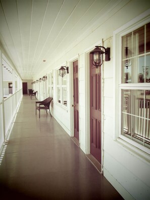 A long corridor with white walls, dark wooden doors, and windows with barred glass. - Brewer Motor Inn (Brewer)