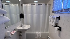 A bathroom with a sink, toilet, and bathtub. There are towels hanging on the wall and a shower curtain.