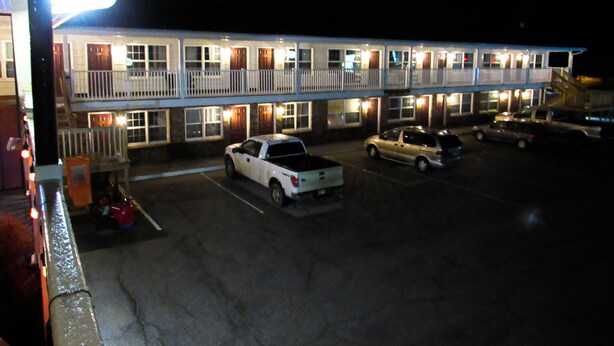 A motel with multiple floors, a parking lot, and several parked vehicles.