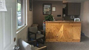 A reception area with a wooden counter, a small desk, and a chair.