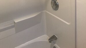 A corner of a room with a bathtub, a showerhead, and a faucet.