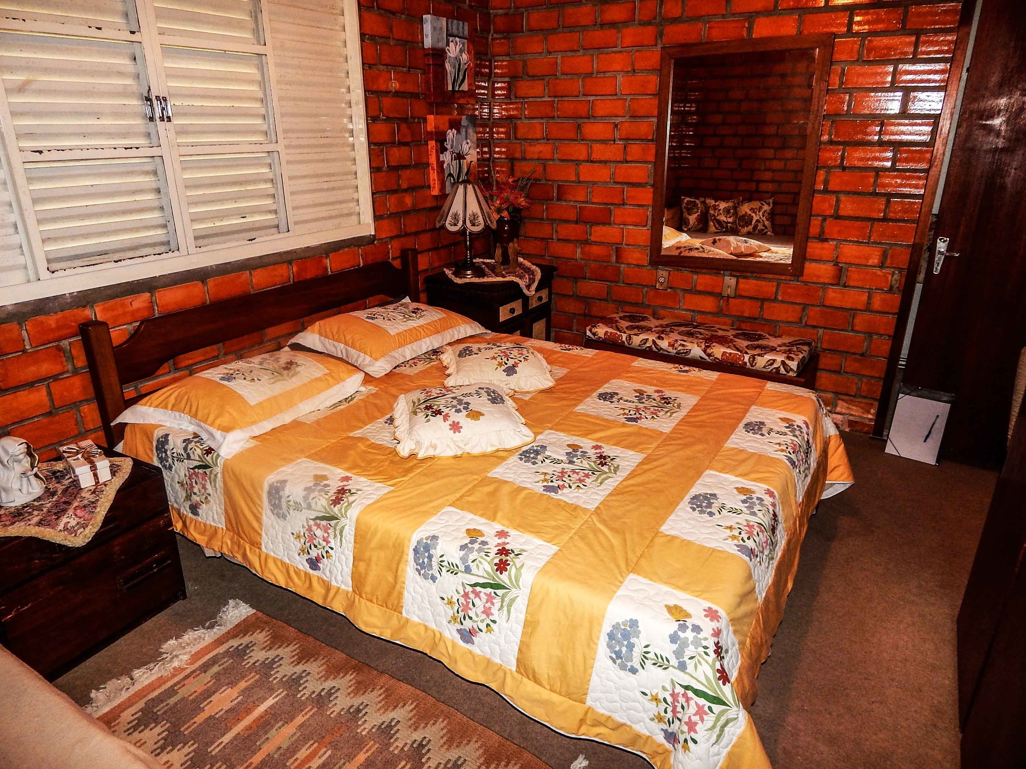 Una camera da letto con una parete in mattoni, un letto con struttura in legno e una coperta a fiori.