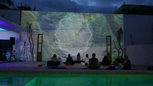 A group of people meditating by a pool with a large screen displaying a mandala in the background. - Radio Tulum Hotel (Tulum)