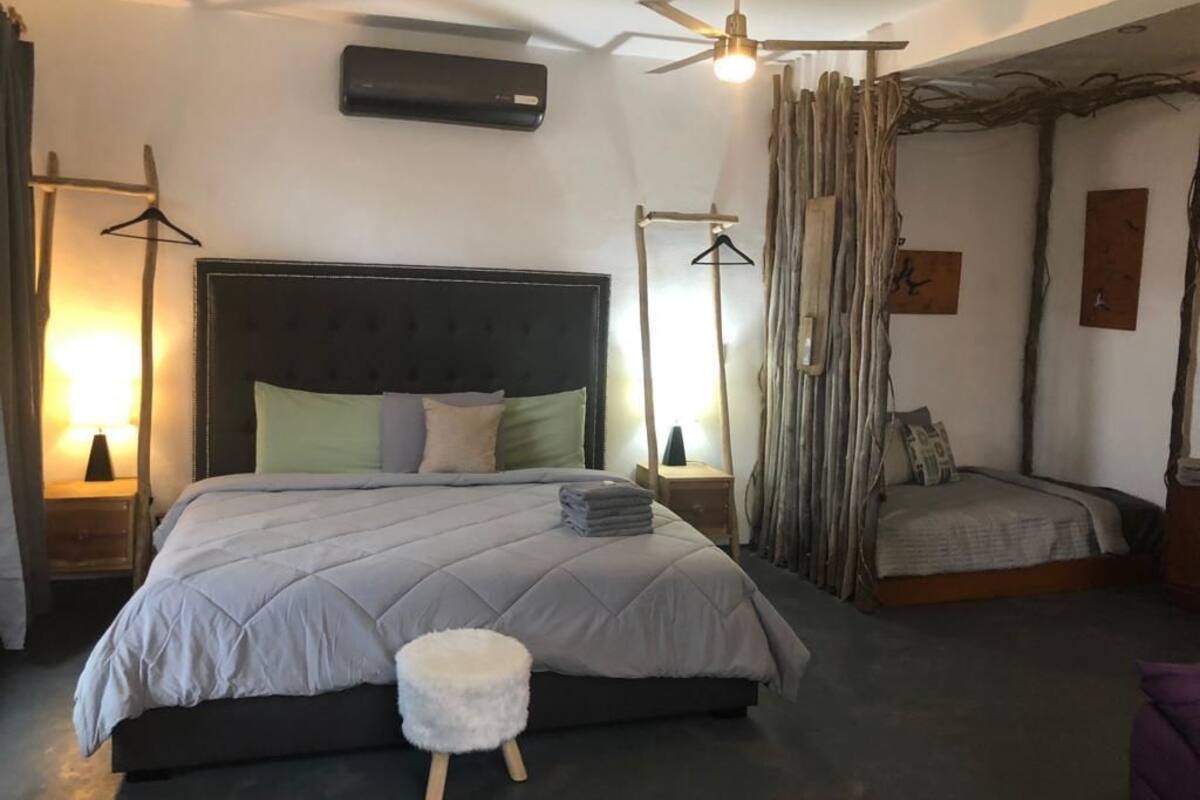 Un dormitorio con una cama grande, una mesita de noche, una lámpara colgante y un ventilador de techo.