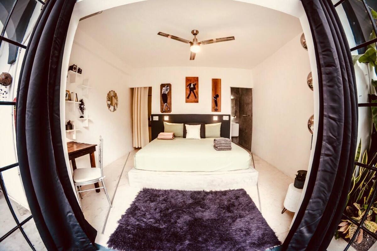 Un dormitorio moderno con cama, ventilador de techo, escritorio y silla.