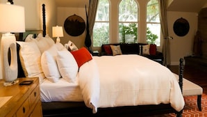 A bedroom with a large bed, a wooden dresser, and a window with curtains.
