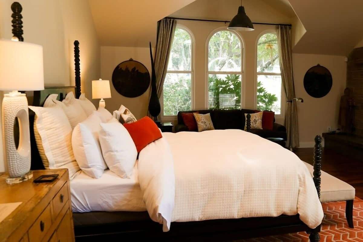 A bedroom with a large bed, a wooden dresser, and a window with curtains.