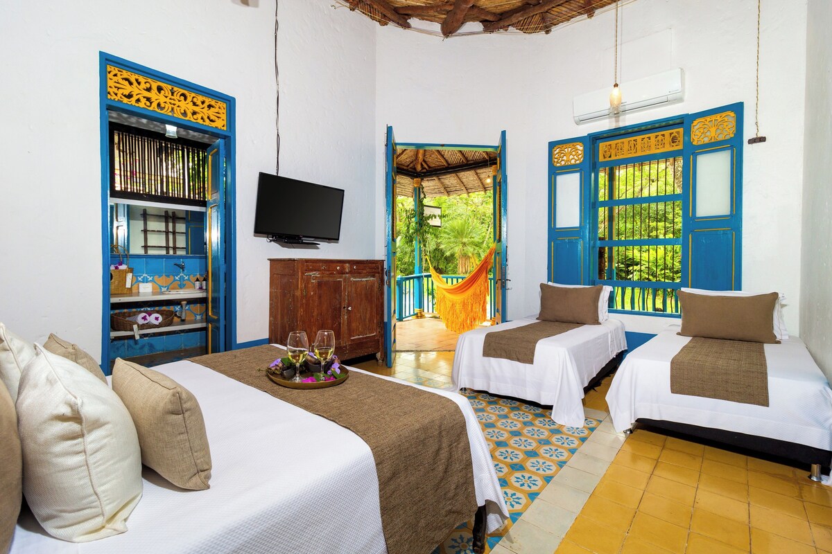 A hotel room with two beds, a TV, and a view of the outdoors.