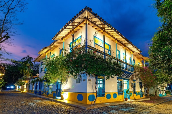 A traditional building with a tiled roof and a balcony, surrounded by cobblestone streets and greenery.