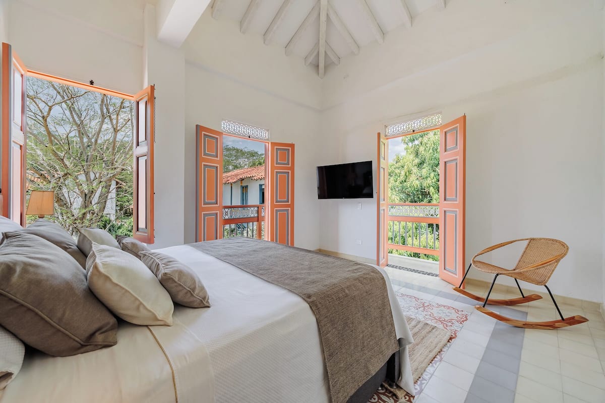 A bedroom with a bed, pillows, a TV, and a rocking chair.