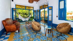 Quarto com rede, duas poltronas de couro, uma mesa pequena e vista para o verde lá fora.