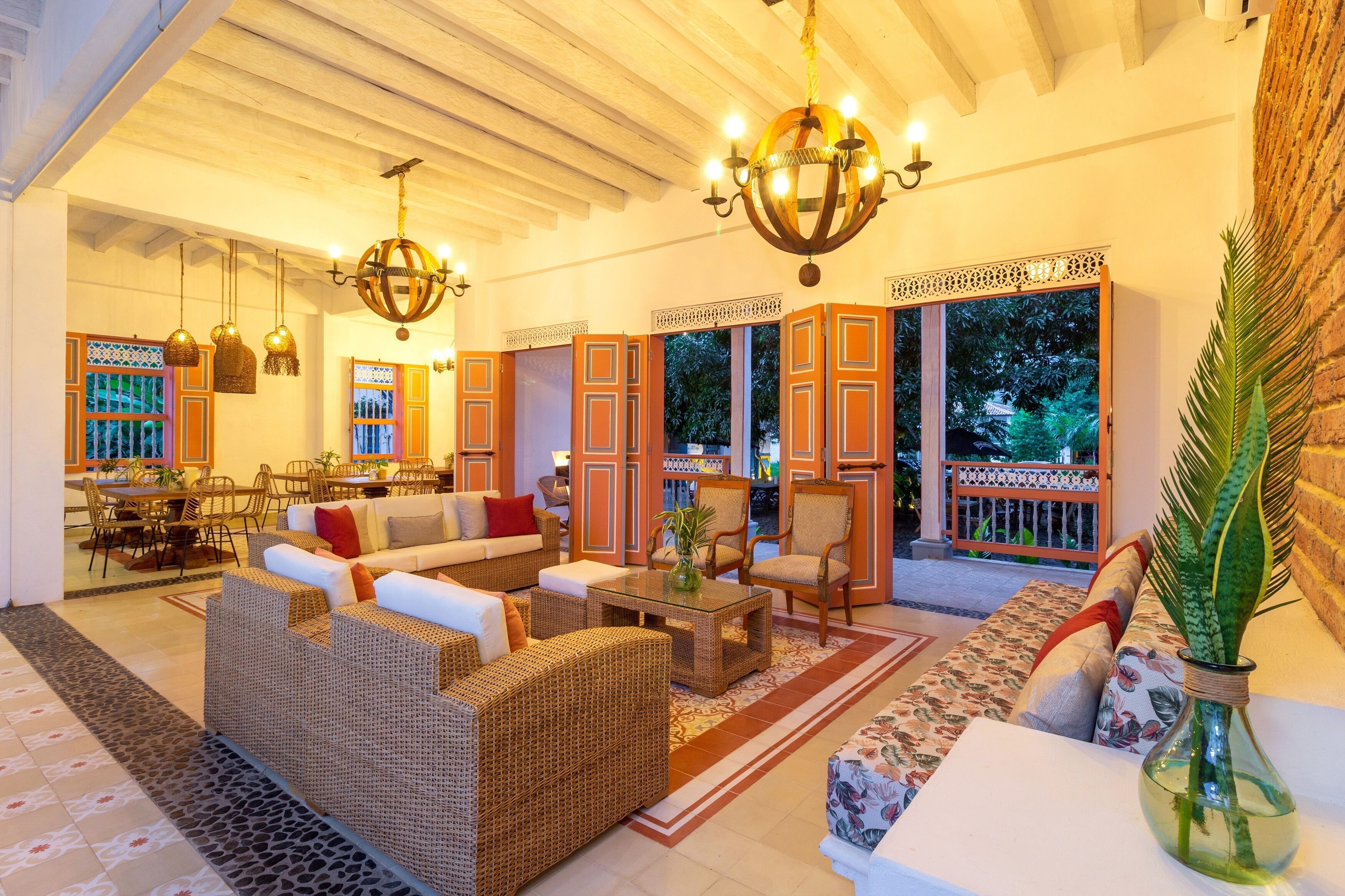 A spacious living area with wicker furniture, a glass coffee table, and a large window with a view of greenery.