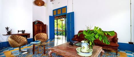 A room with a patterned floor, a wooden coffee table, a sofa, and a chair.
