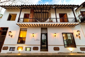 A two-story building with a balcony, a door labeled "CASA LA BODEGUITA," and wall-mounted lights.
