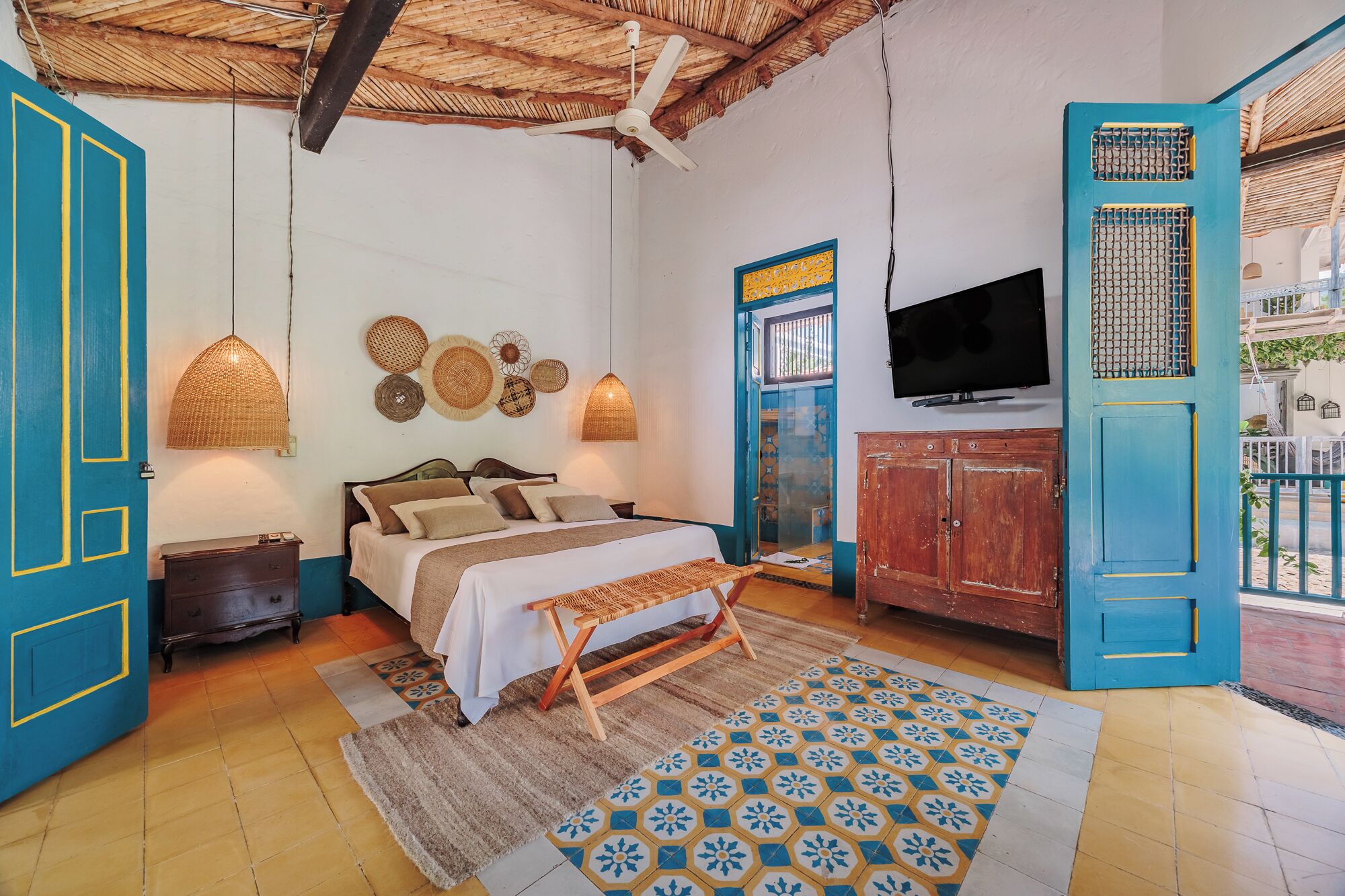 Un dormitorio con cama, lámparas de noche, televisor y vistas al exterior.