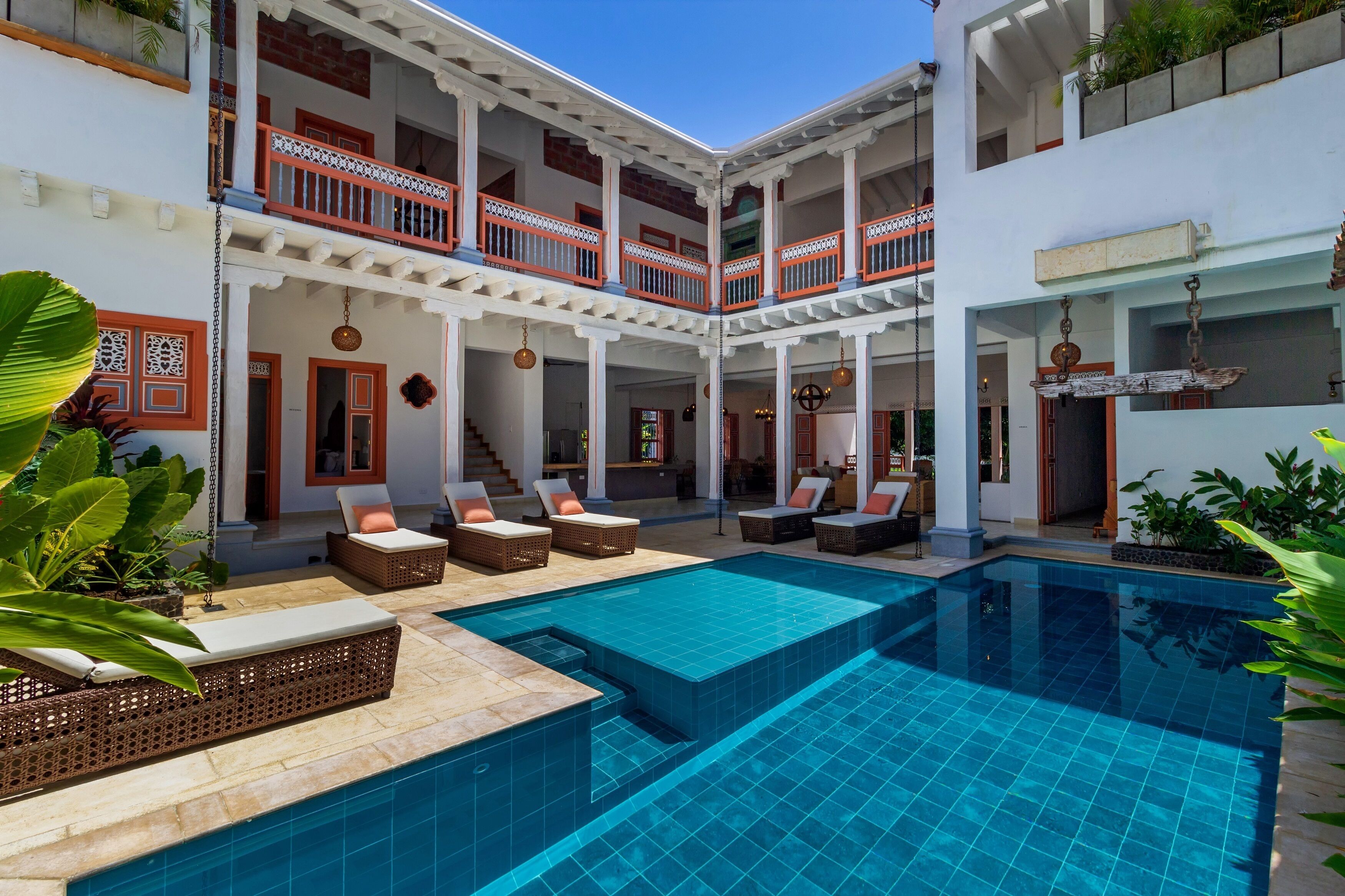 A pool area with lounge chairs and a two-story building with balconies.