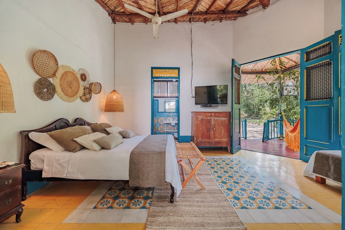A bedroom with a bed, a TV, a wooden cabinet, and a hammock.