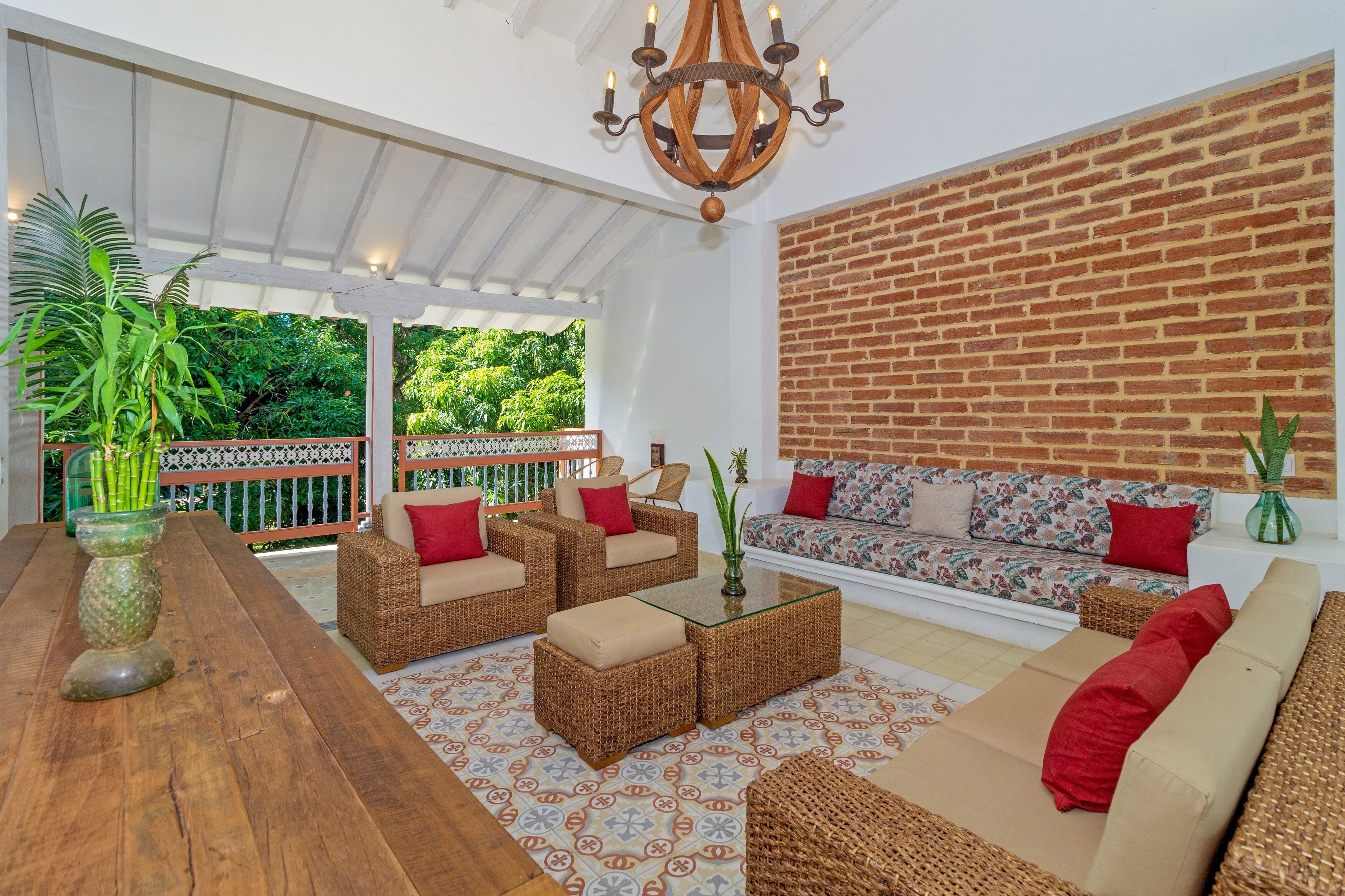 A spacious patio with wicker furniture, a wooden table, and a brick wall.
