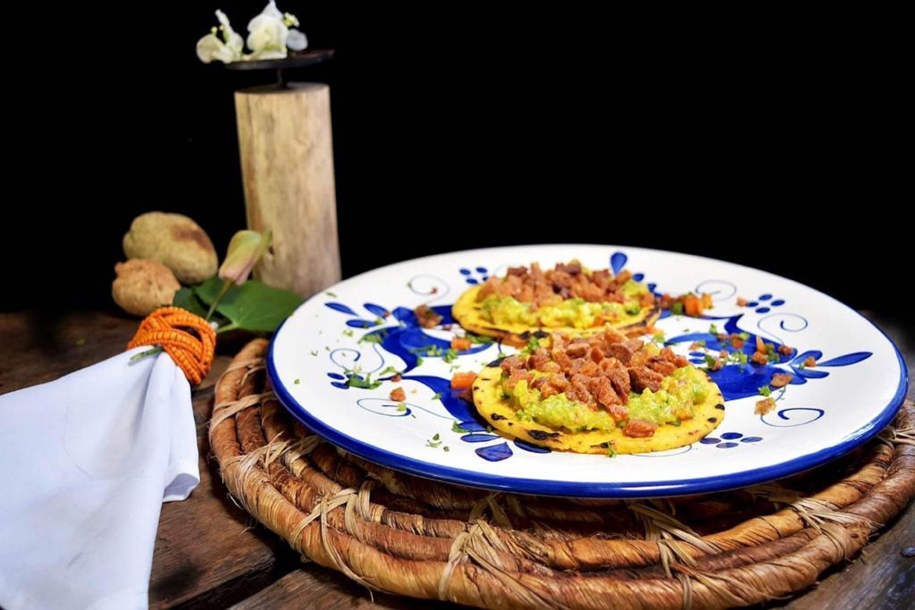 Un plato con dos porciones de comida sobre un plato decorativo, colocado sobre un tapete tejido.