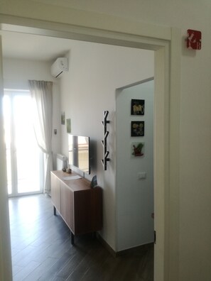 A modern room with a wooden dresser, a mirror, and a door leading to another space. - Maison Lumière (Salerno)