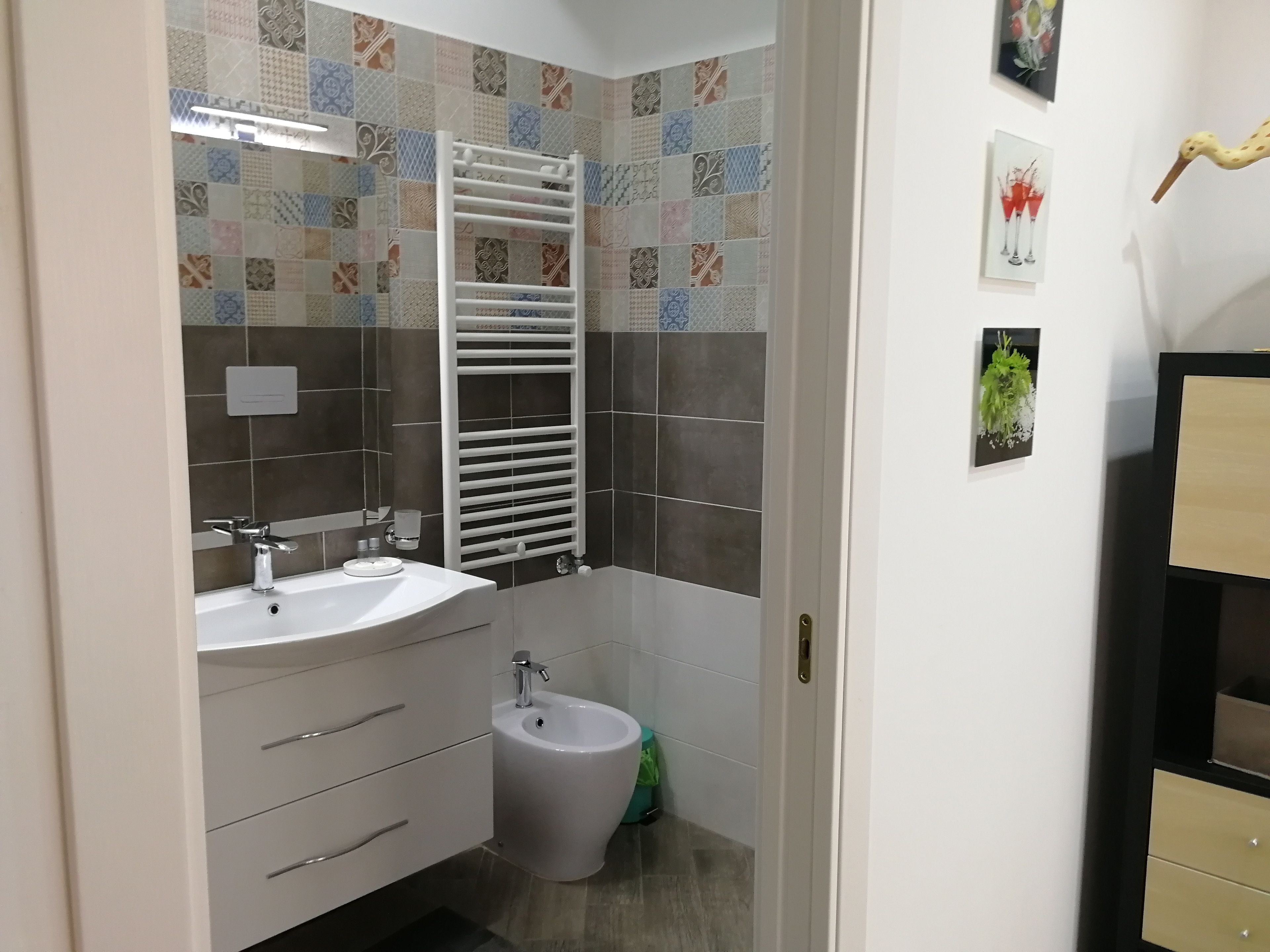 A bathroom with a white sink, a bidet, a towel rack, and a mirror.