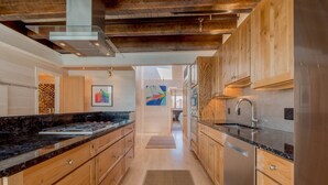 Una cocina moderna con armarios de madera, un refrigerador de acero inoxidable y una encimera negra.