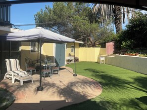A patio with a table and chairs, a covered seating area, and a well-maintained lawn.